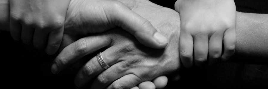 Black and white close up image of a family holding each other's hands in a horizontal and vertical fashion