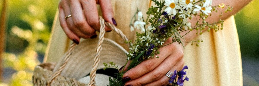 The close up of a woman's pretty hands holding a small wicker basket with pretty spring flowers in it