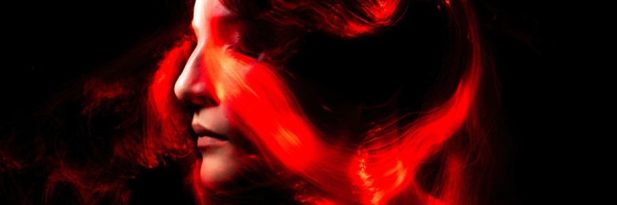 The abstract image of the side profile of a woman's face with red color swirling across and around it