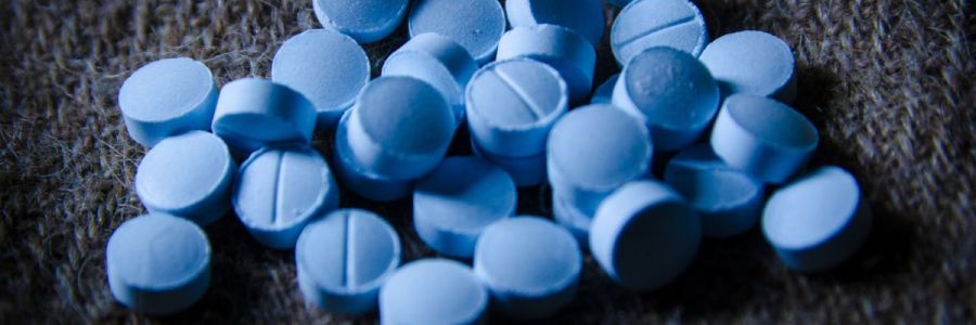 A clutter of circular blue pills against a dark woolen background